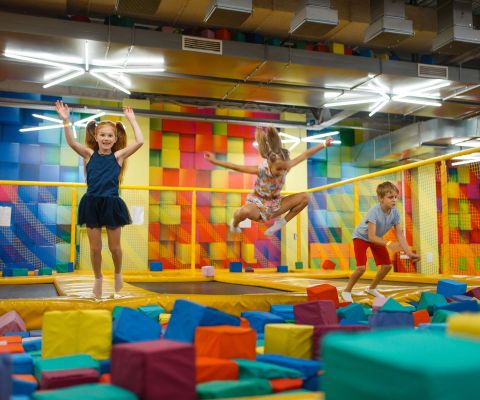 Bambini che saltano sui tappeti elastici nel parco al coperto