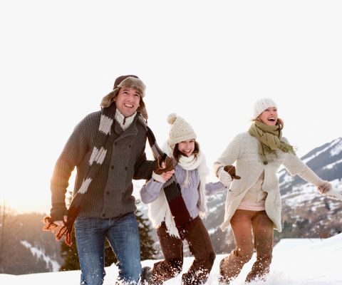 Familie läuft lachend durch den Schnee