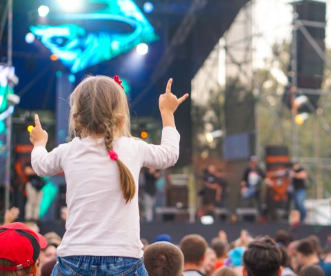 Ein kleines Mädchen auf einem Festival schaut auf die Bühne