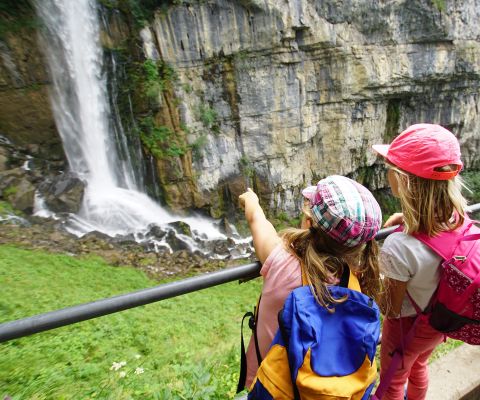 Zwei Kinder bestaunen einen Wasserfall. 
