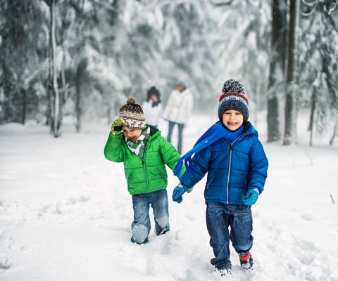Zwei kleine Jungen stapfen lachend durch den Schnee