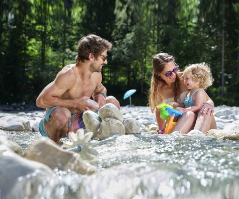 Des parents se baignent dans une rivière avec leur jeune enfant
