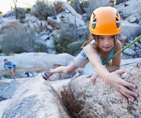Bambina si arrampica in cordata su una parete rocciosa