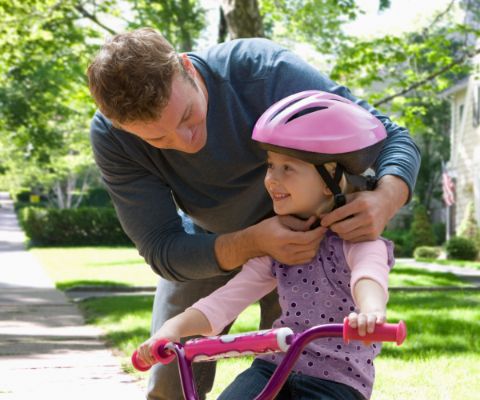 Un padre chiude il casco da bici alla figlia