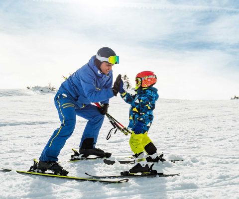 Un bambino piccolo impara a sciare e si tiene alle racchette