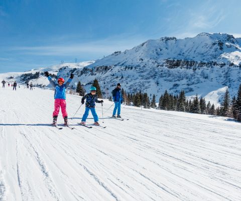 Familie fährt Ski auf einer breiten Skipiste