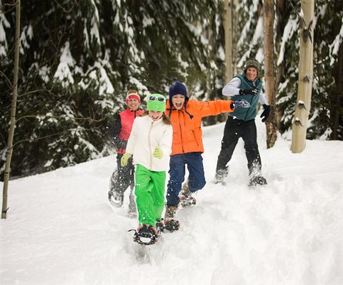 Familie mit grösseren Kindern haben Spass beim beim Schneeschuhlaufen