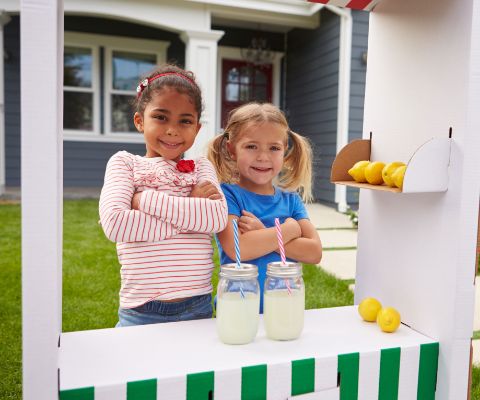 Deux fillettes vendent de la limonade faite maison.
