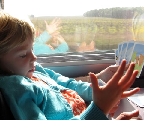 Kind im Zug mit Spielkarten in der Hand