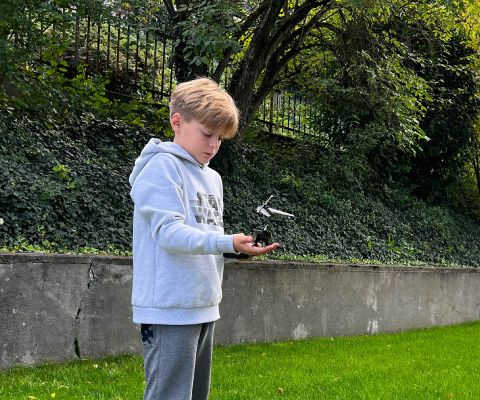 Dans un jardin, un garçon tient le «FLYBOTIC Sky Cheetah» à la main