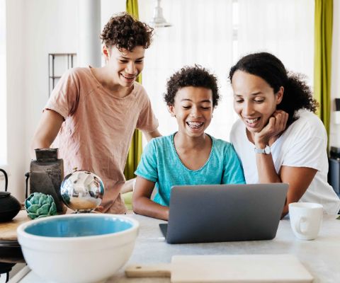 Mutter mit Söhnen gestalten digitale Einladungen am Laptop