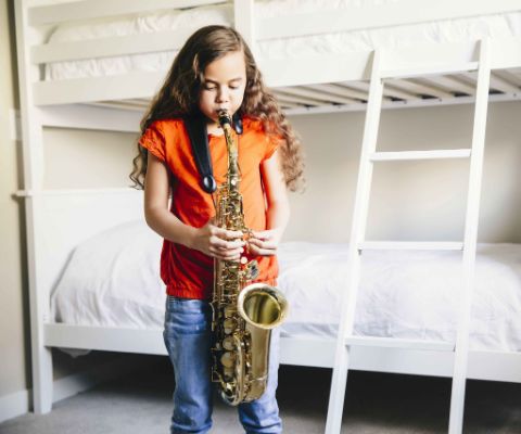 Una bambina si esercita a casa con il suo strumento musicale