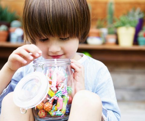 Bambino che guarda in un vaso contenente dolciumi