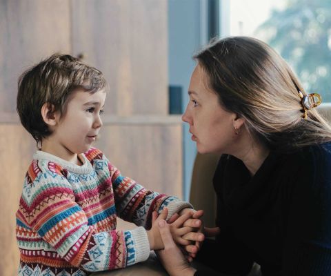 Mutter und Sohn sprechen miteinander und halten sich an der Hand.