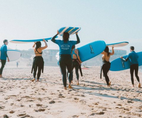 Des surfeurs marchent en direction de la mer avec leur planche sur la tête