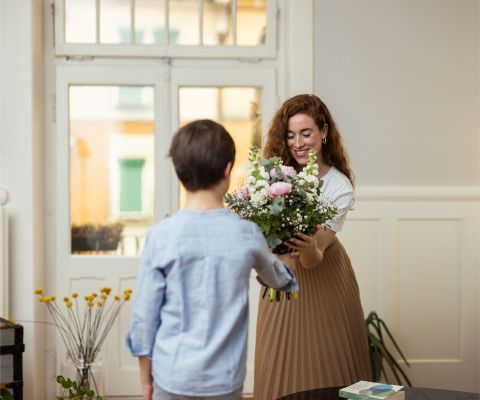 Ein Junge überreicht einer Frau einen Blumenstrauss
