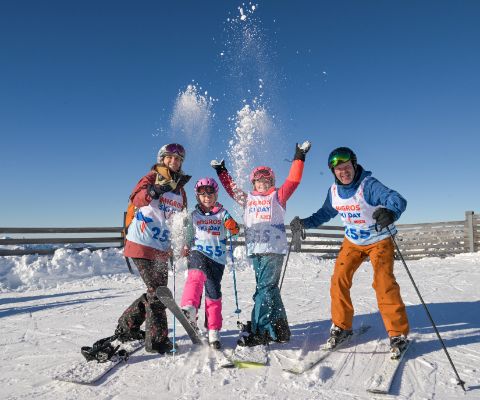 Une famille à skis dans la neige lors du Migros Ski Day