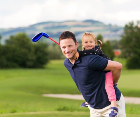Papà con la mazza da golf e la figlia a cavalluccio
