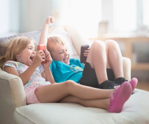 Enfants en train de jouer à des jeux en ligne sur le canapé