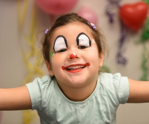 Lachendes Mädchen als Clown geschminkt