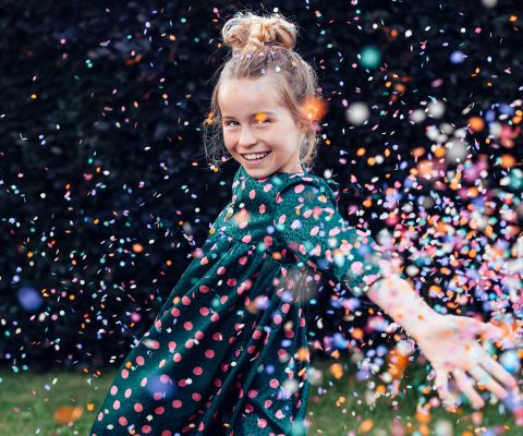 Strahlendes Mädchen freut sich unter einem Konfettiregen über ihren Geburtstag