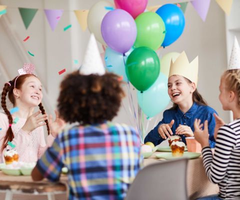 Kinder feiern Kindergeburtstag mit Ballonen und Cupcakes
