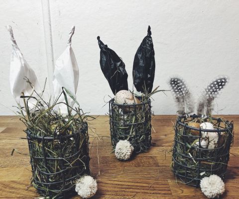 Trois nids de Pâques dans une corbeille en fil de fer avec des oreilles de lapin