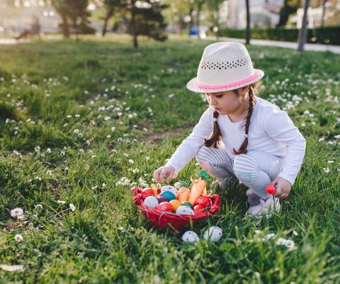Mädchen mit einem Osternest auf einer Frühlingswiese