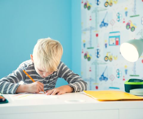 Un bambino fa i compiti seduto alla scrivania