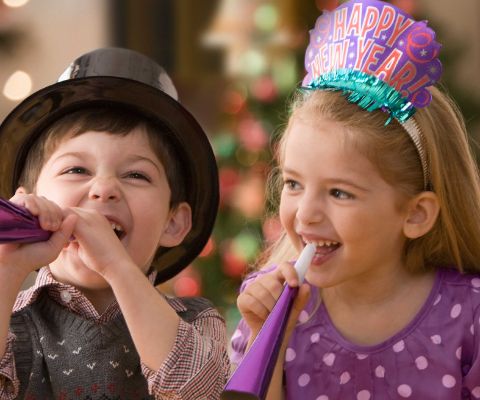 Bube und Mädchen mit Neujahrs-Gadgets und Plastikpfeiffen