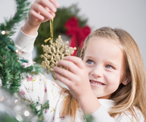 Una bambina decora un albero di Natale