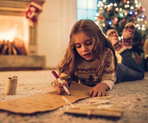 Une fillette écrit sa liste de vœux pour Noël