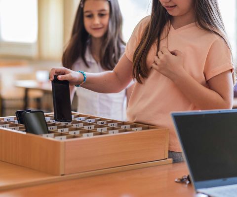 Zwei Mädchen in der Schule, die ihr Handy abgeben