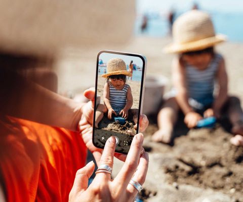 Mutter fotografiert Tochter beim Sand spielen