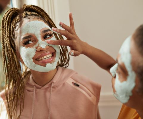 Une adolescente applique un masque pour le visage à son amie.