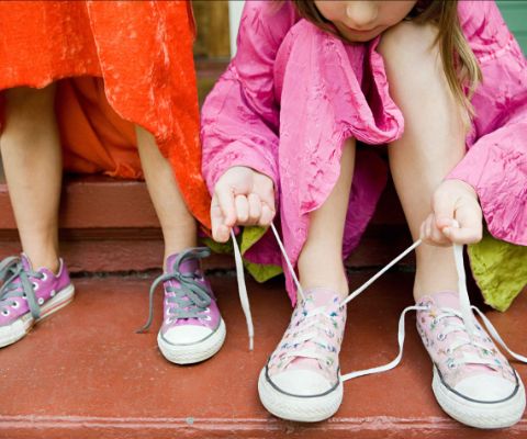 Mädchen halten Schuhbändel und binden ihre Schuhe