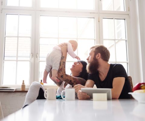 Mutter hält das Baby hoch und Vater schaut zu Mutter hält das Baby hoch und Vater schaut zu