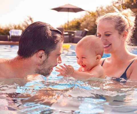 Dei genitori nuotano in piscina con un bebè