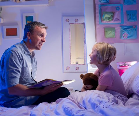 Papà mentre legge una storia alla figlia a letto
