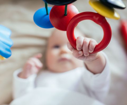 Un bebè afferra un anello di presa mentre è sdraiato