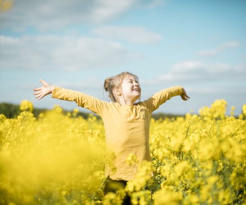 Une jeune fille profite du printemps dans un champ de colza