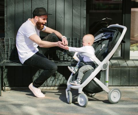 Un papà gioca col figlio sul passeggino