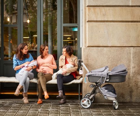 Schwangere und zwei junge Mütter unterhalten sich vor einem Café
