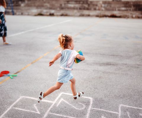 Kind rennt über den Schulhof mit einem Ball