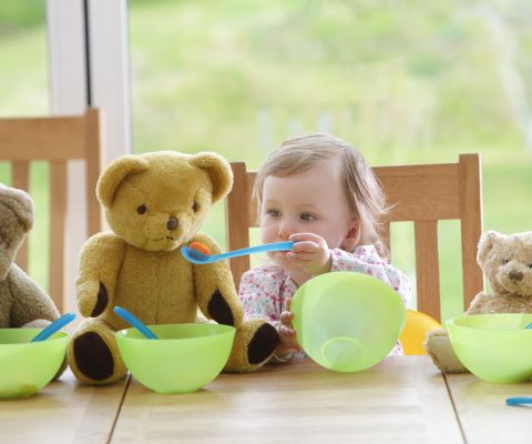 Una bimba piccola dà da mangiare ai suoi orsetti