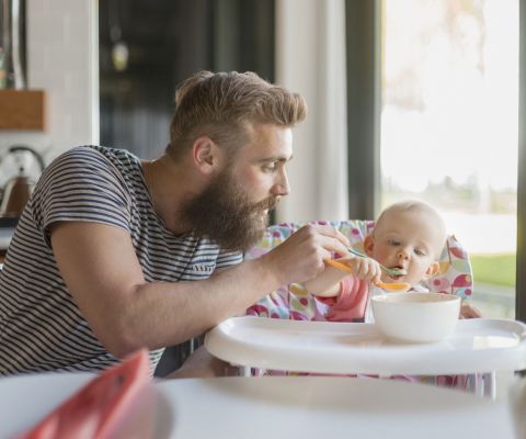 Ein Vater füttert sein Baby mit Brei