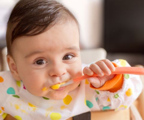 Baby isst Brei mit einem Kinderlöffel