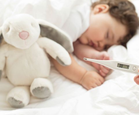 Baby schläft mit Plüschhase - Thermometer mit 38 Grad wird angezeigt