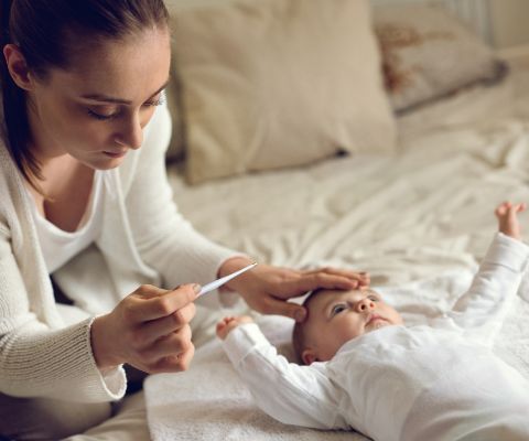 Mamma con bebè e un termometro in mano