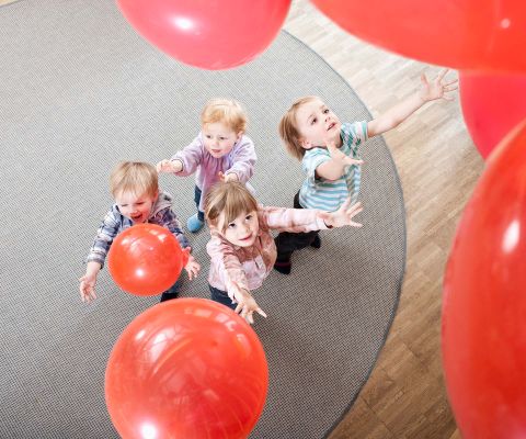 De petits enfants jouant avec des ballons de baudruche rouges